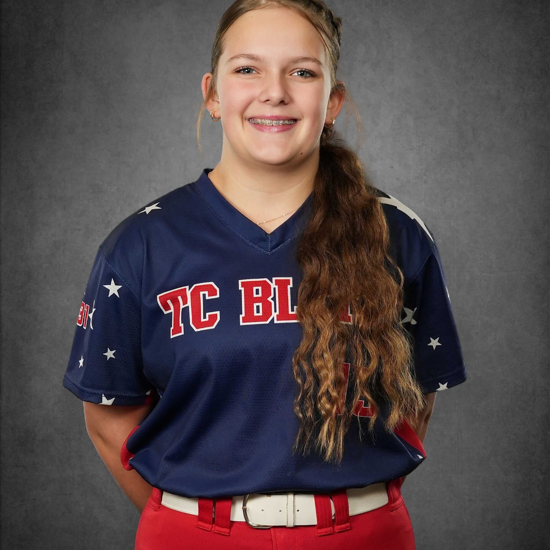 Young athlete in navy jersey with red lettering and red belt, smiling against a gray studio backdrop