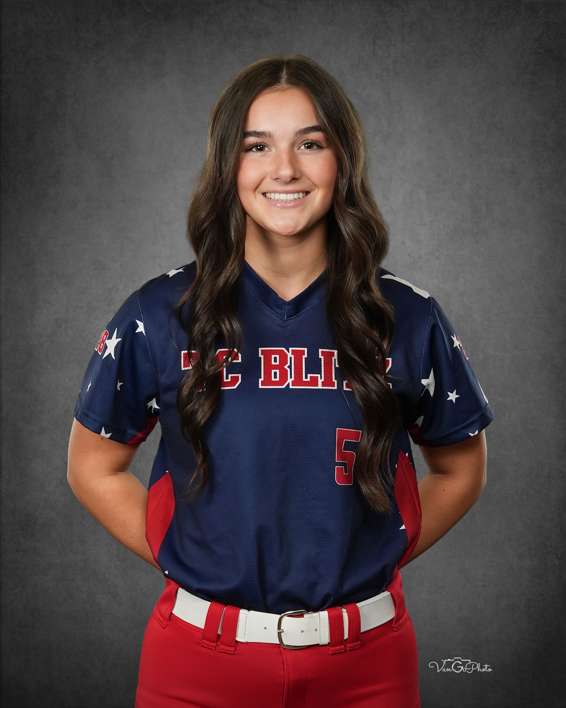 Portrait of a smiling athlete in a navy jersey and red pants against a gray studio backdrop