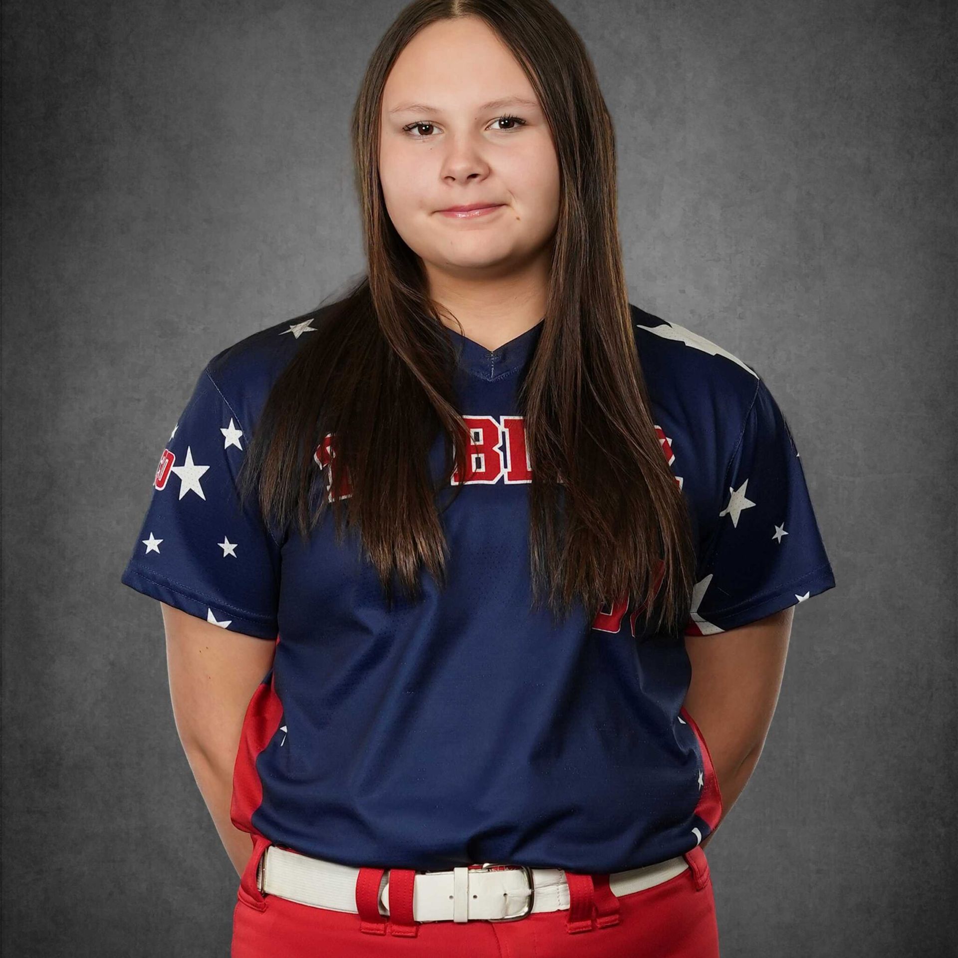 Person in a navy, red, and white sports uniform posing against a gray studio backdrop.