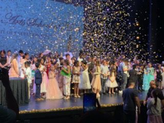 Children on stage during awards ceremony; confetti falling.