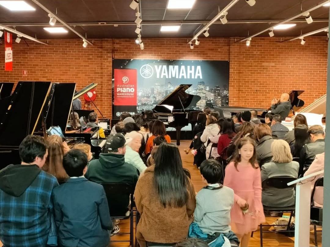 Audience watches a Yamaha piano demonstration in a music store.