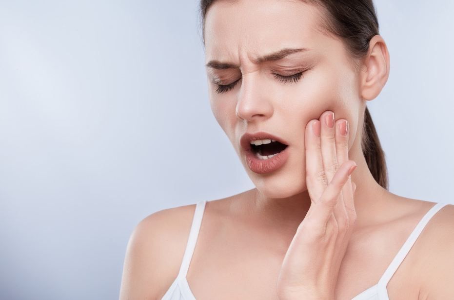 a woman is holding her face in pain because of a toothache .