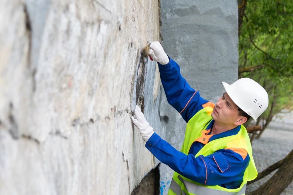 Man Wearing a Hard Hat and Safety Vest is Working on a Wall — Capital Ultimate Facility in Gungahlin, ACT