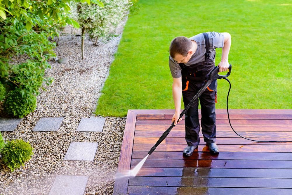 Man is Using a High Pressure Washer to Clean a Wooden Deck — Capital Ultimate Facility in Beard, ACT