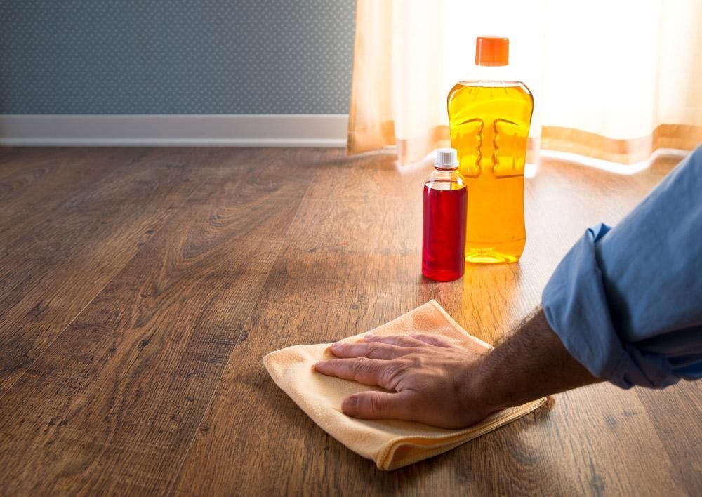 Person is Cleaning a Wooden Floor With a Cloth — Capital Ultimate Facility in Woden, ACT