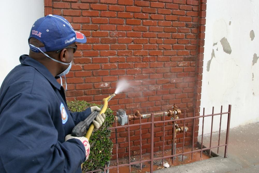 Man Spraying a Brick Wall With a Hose — Capital Ultimate Facility in Beard, ACT