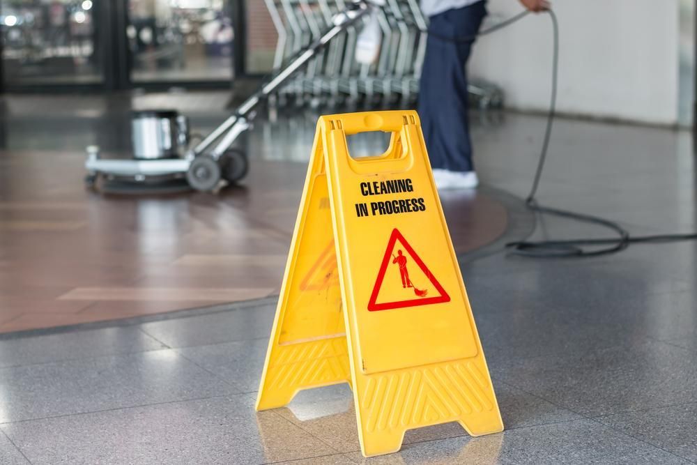 Yellow Caution Sign is Sitting on the Floor Next to a Vacuum Cleaner — Capital Ultimate Facility in Beard, ACT