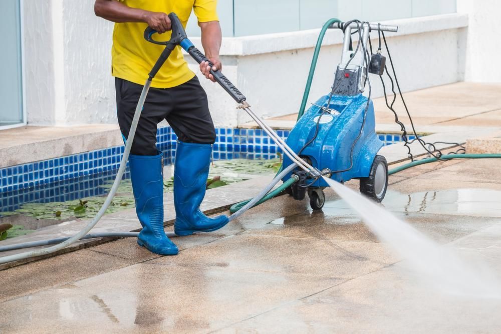 Man is Cleaning the Sidewalk With a High Pressure Washer — Capital Ultimate Facility in Beard, ACT