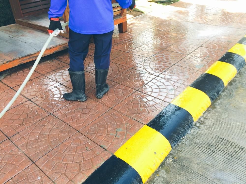 Person is Spraying Water on a Tiled Floor With a Hose — Capital Ultimate Facility in Canberra, ACT