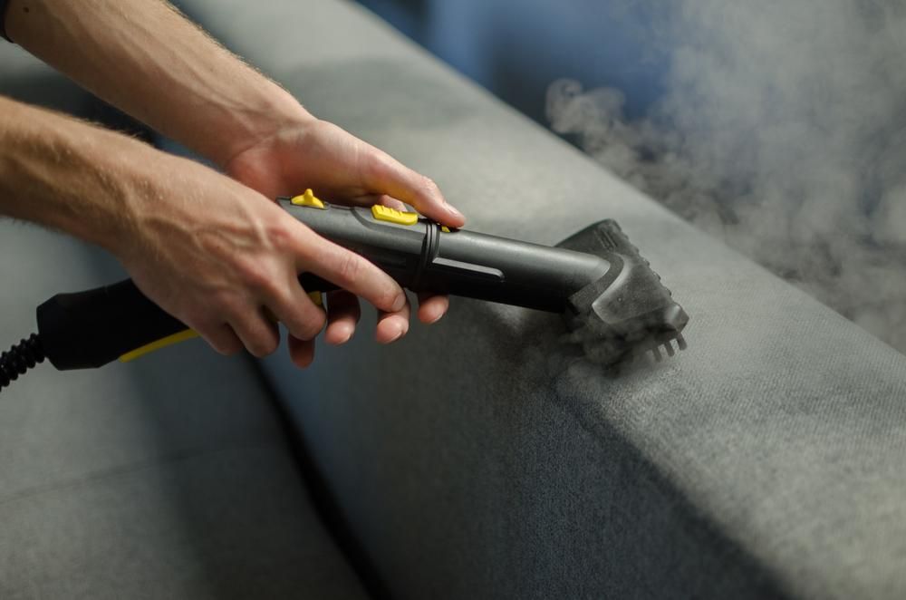 Person is Cleaning a Couch With a Steam Cleaner — Capital Ultimate Facility in Gungahlin, ACT