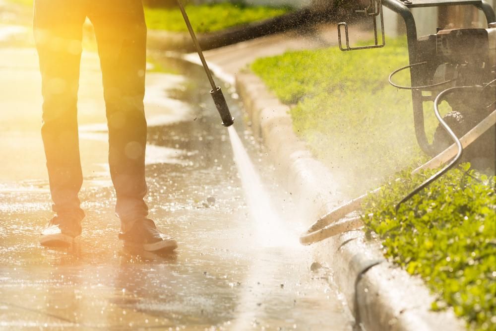 Man is Using a High Pressure Washer to Clean a Sidewalk — Capital Ultimate Facility in Tuggeranong, ACT