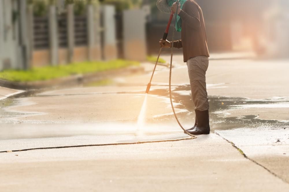 Man is Cleaning the Sidewalk With a High Pressure Washer — Capital Ultimate Facility in Gungahlin, ACT