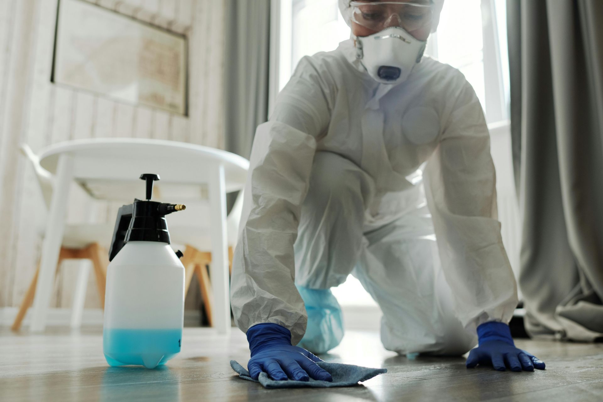 A man in a protective suit is cleaning the floor in a living room. — Capital Ultimate Facility in Beard, ACT