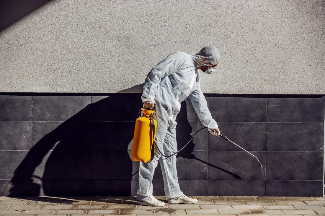 Man in a Protective Suit is Spraying a Wall With a Sprayer — Capital Ultimate Facility in Tuggeranong, ACT