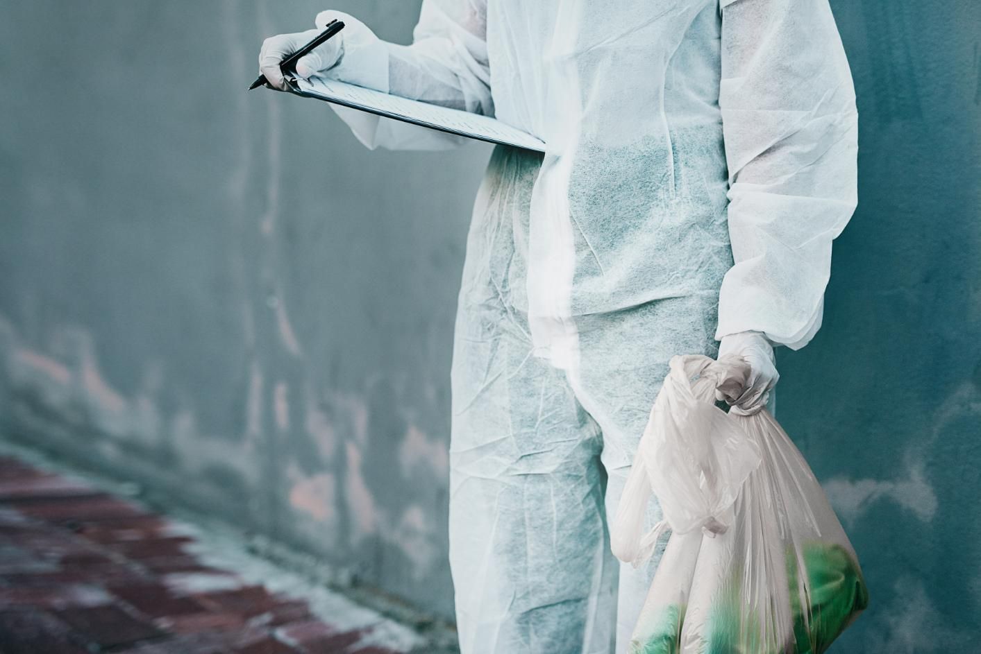 Man in a Protective Suit is Holding a Clipboard and a Bag of Trash — Capital Ultimate Facility in Gungahlin, ACT