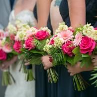 People holding pink and white flower bouquets with green stems, likely at a wedding