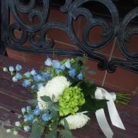 Bouquet of white, blue, and green flowers resting against a black wrought-iron gate