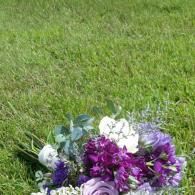 Bouquet of purple, white, and green flowers on grass near the bottom of the frame