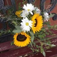 Sunflowers and white daisies in a vase on a red wooden bench