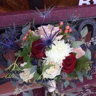 Bouquet of red roses, white flowers, and purple accents in a decorative arrangement