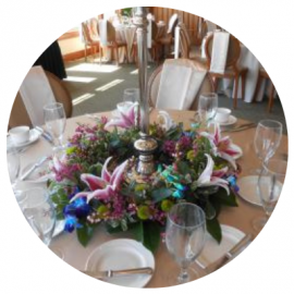 Flower centerpiece on a round banquet table set with wine glasses and plates