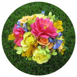 Colorful bouquet of mixed flowers on green grass, with pink, yellow, and orange blooms