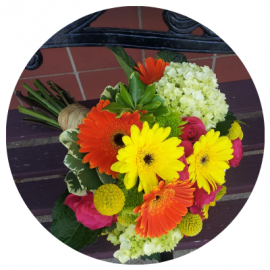 Bright mixed bouquet with red, yellow, pink, and white flowers wrapped in paper