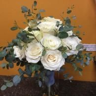 White roses and eucalyptus in a bouquet against an orange wall