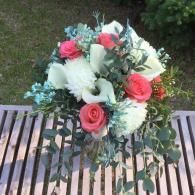 Pink and white flower bouquet on a wooden bench outdoors