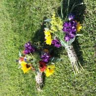 Two small bouquets of colorful flowers arranged in wicker baskets on grass