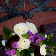 White and purple flower bouquet against a brick wall and black iron gate