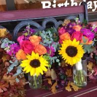 Colorful flower bouquets in glass vases with sunflowers on a birthday display