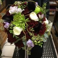 Bouquet of burgundy, white, and green flowers in a black vase on a counter