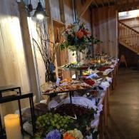 Elegant buffet table with floral centerpieces and assorted dishes in a warmly lit hallway