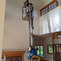 A man is standing on a lift in a living room.