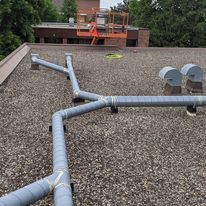 There are a lot of pipes on the roof of a building.