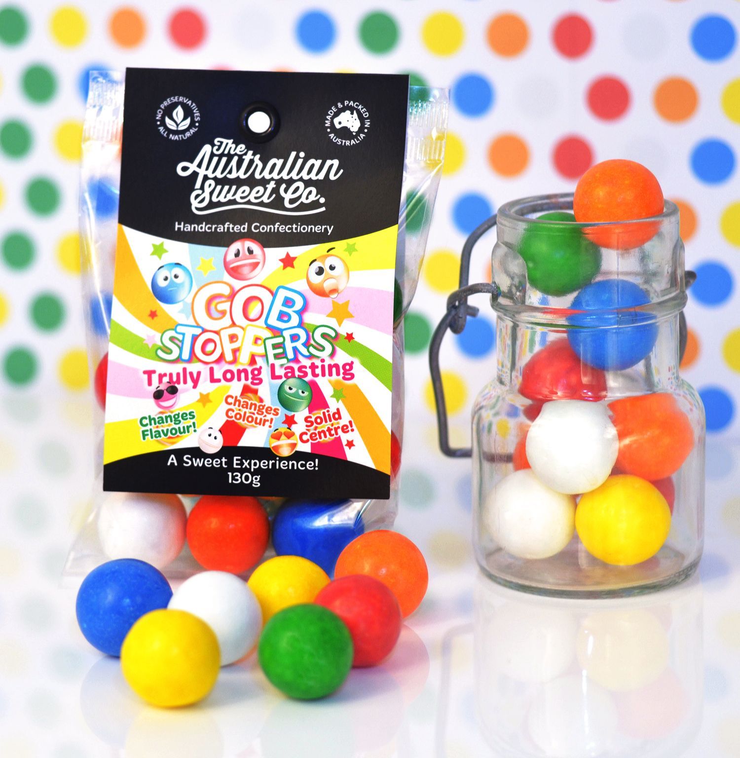Australian Sweet Co. candy box beside a glass jar of colorful gumballs on a polka-dot background