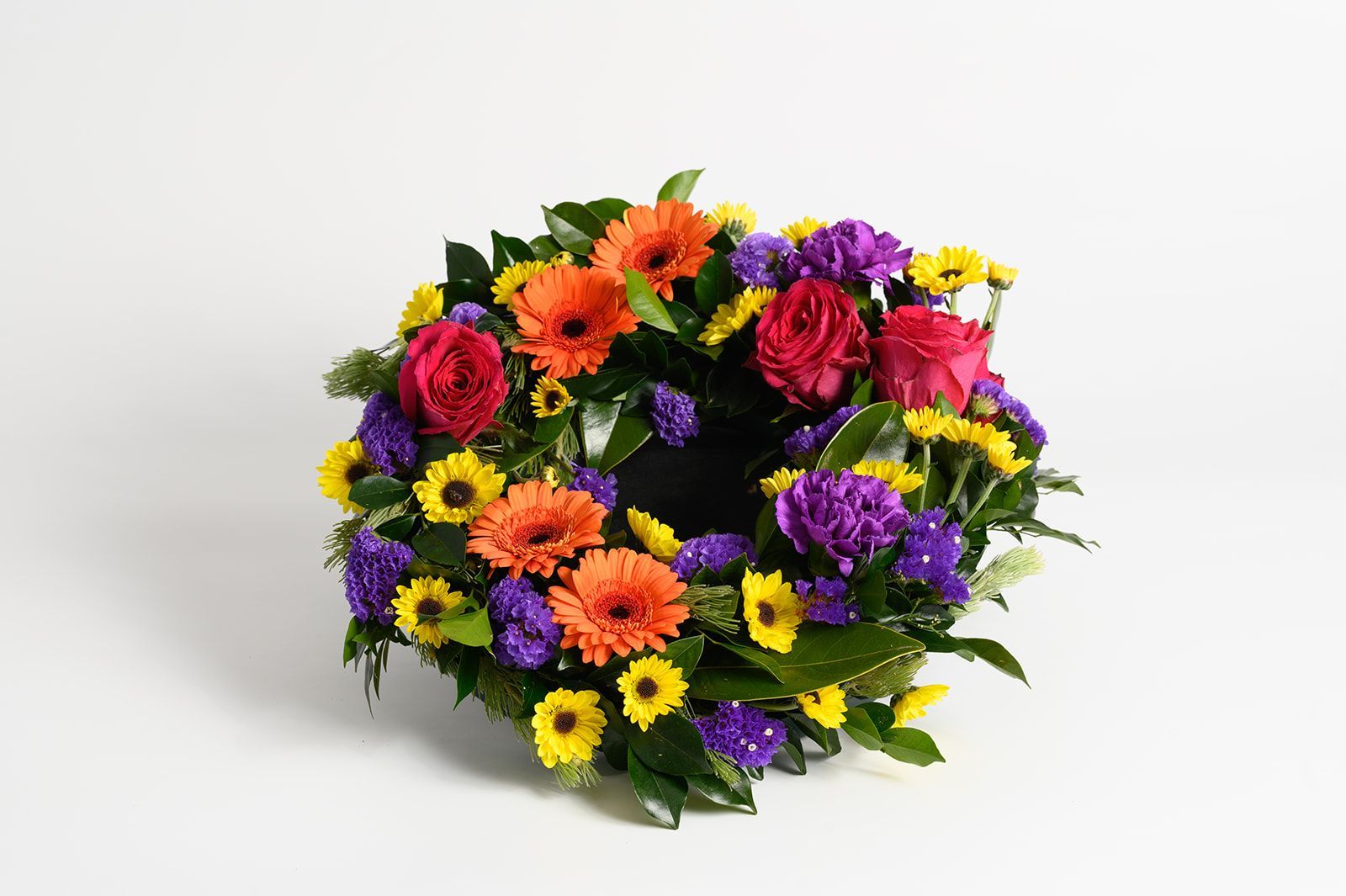 Colorful wreath of mixed flowers in red, orange, purple, and yellow on a white background