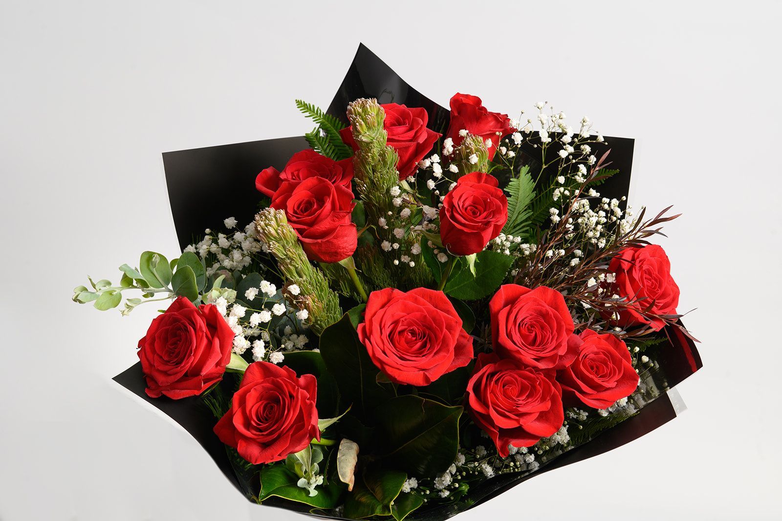 Bouquet of red roses with white baby's breath and dark wrapping paper