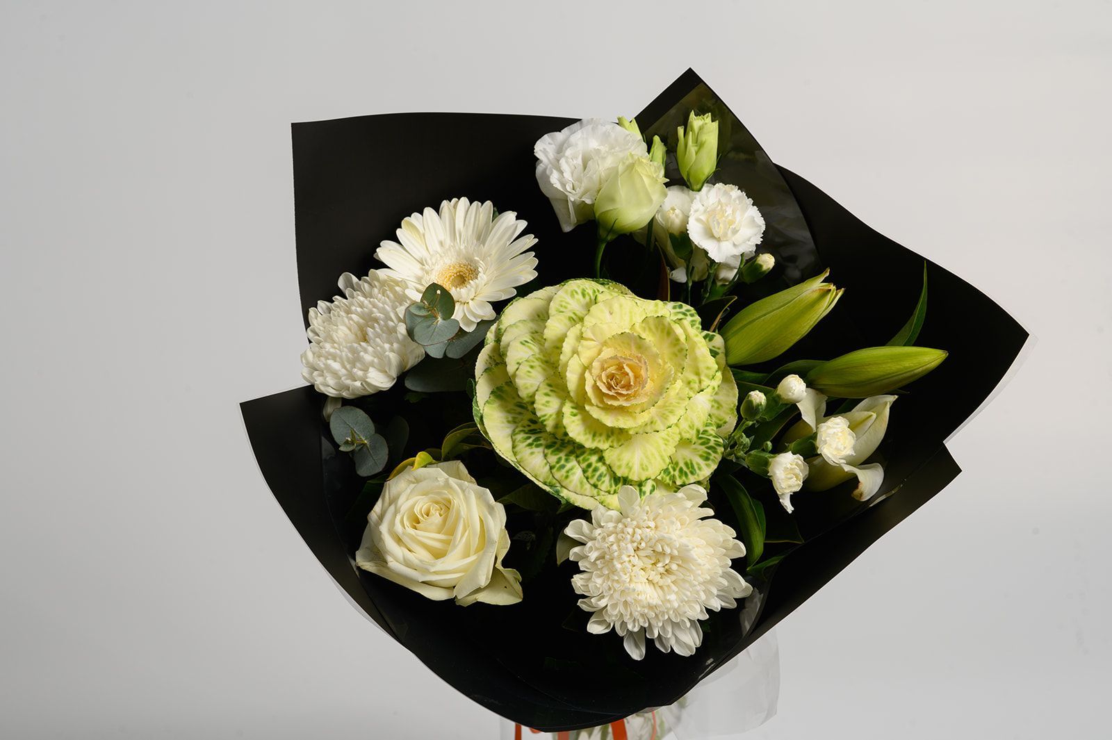 White and pale green flower bouquet wrapped in black paper