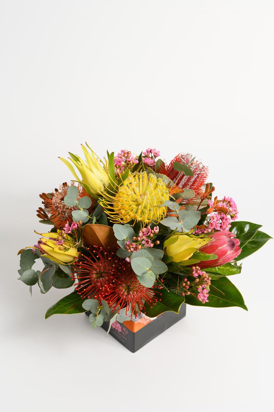 Colorful mixed flower bouquet in a black box with yellow, pink, red, and green blooms