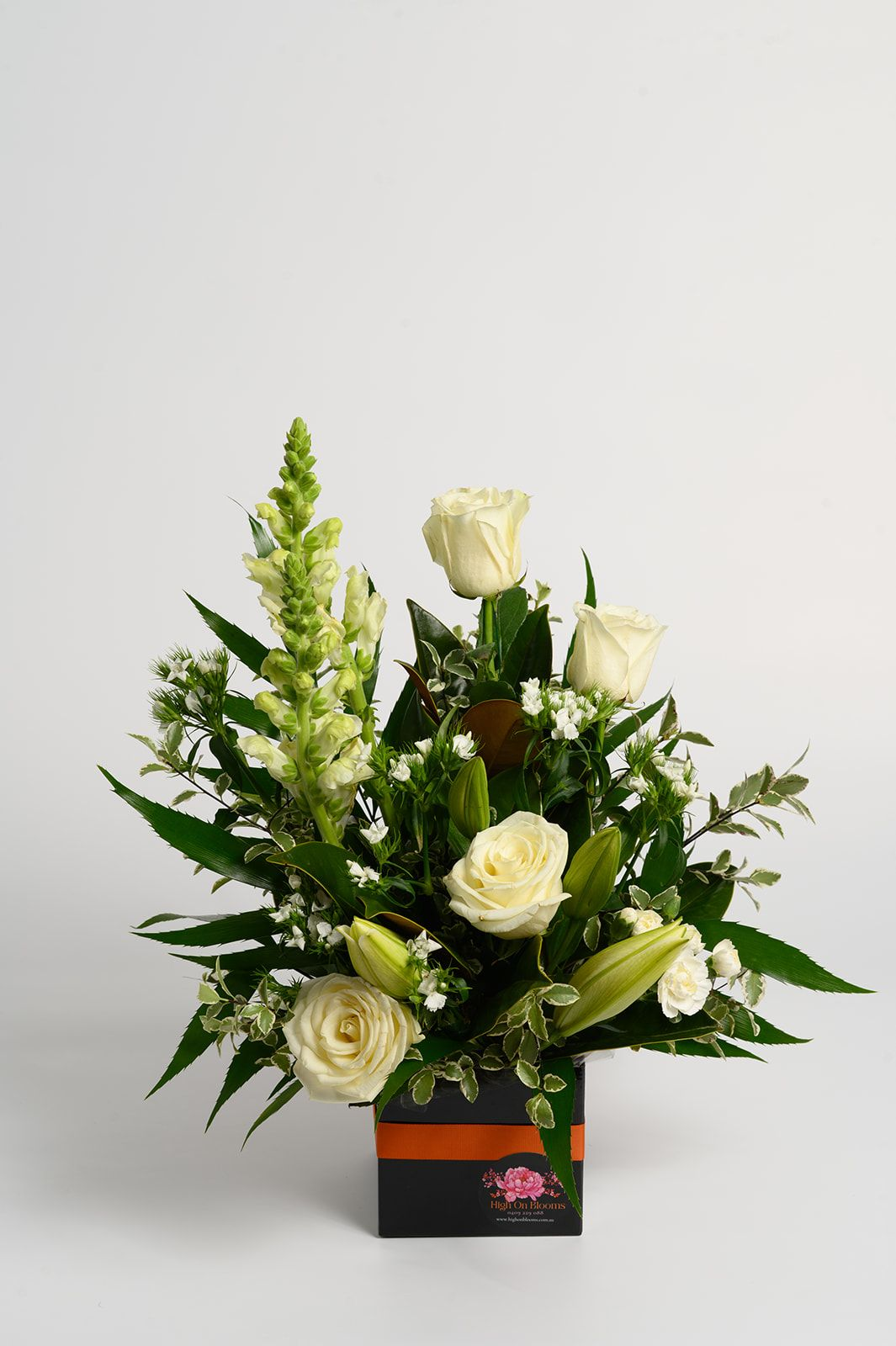 White rose floral arrangement in a black and orange box on a light background