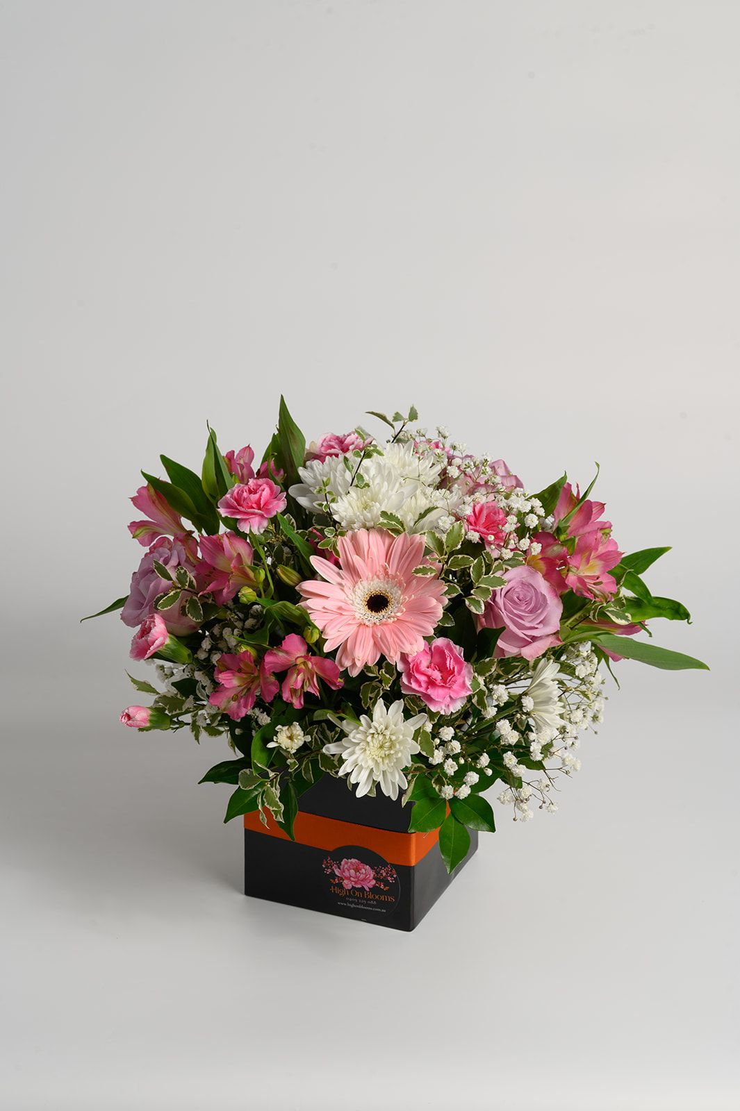 Pink and white flower arrangement in a black vase on a plain gray background