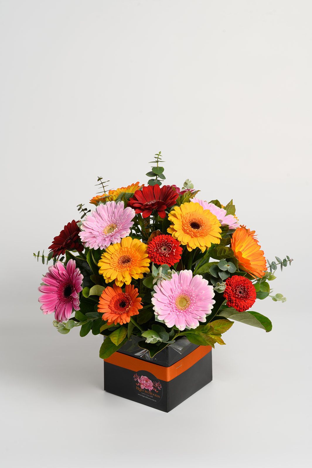 Colorful mixed flower bouquet in a black square vase on a white background