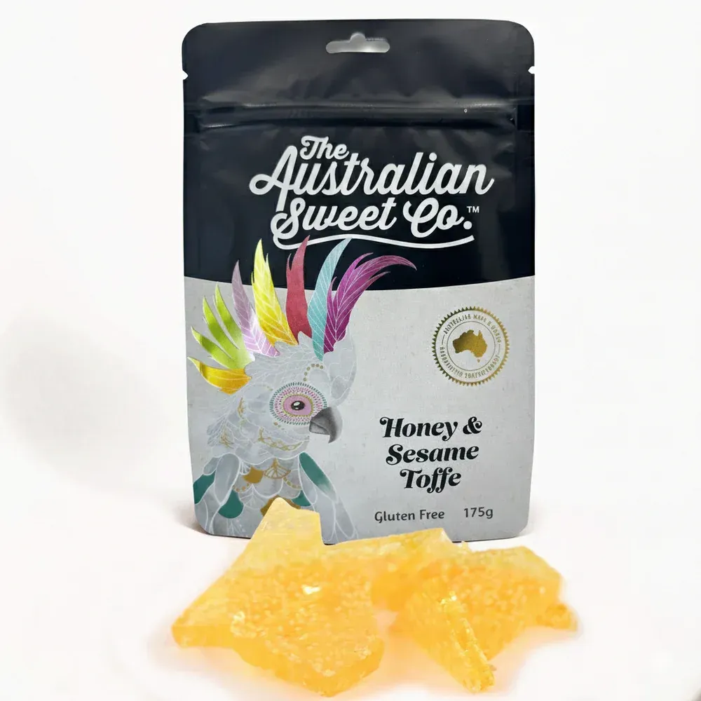 Australian Sweet Co. honey and sesame toffee bag with yellow candy pieces on white background