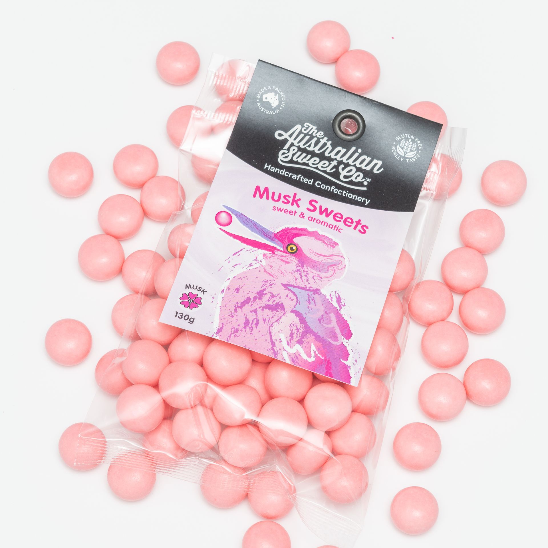 Pink candy beads scattered around a Musk Sweets packet with a pink illustrated animal on the front