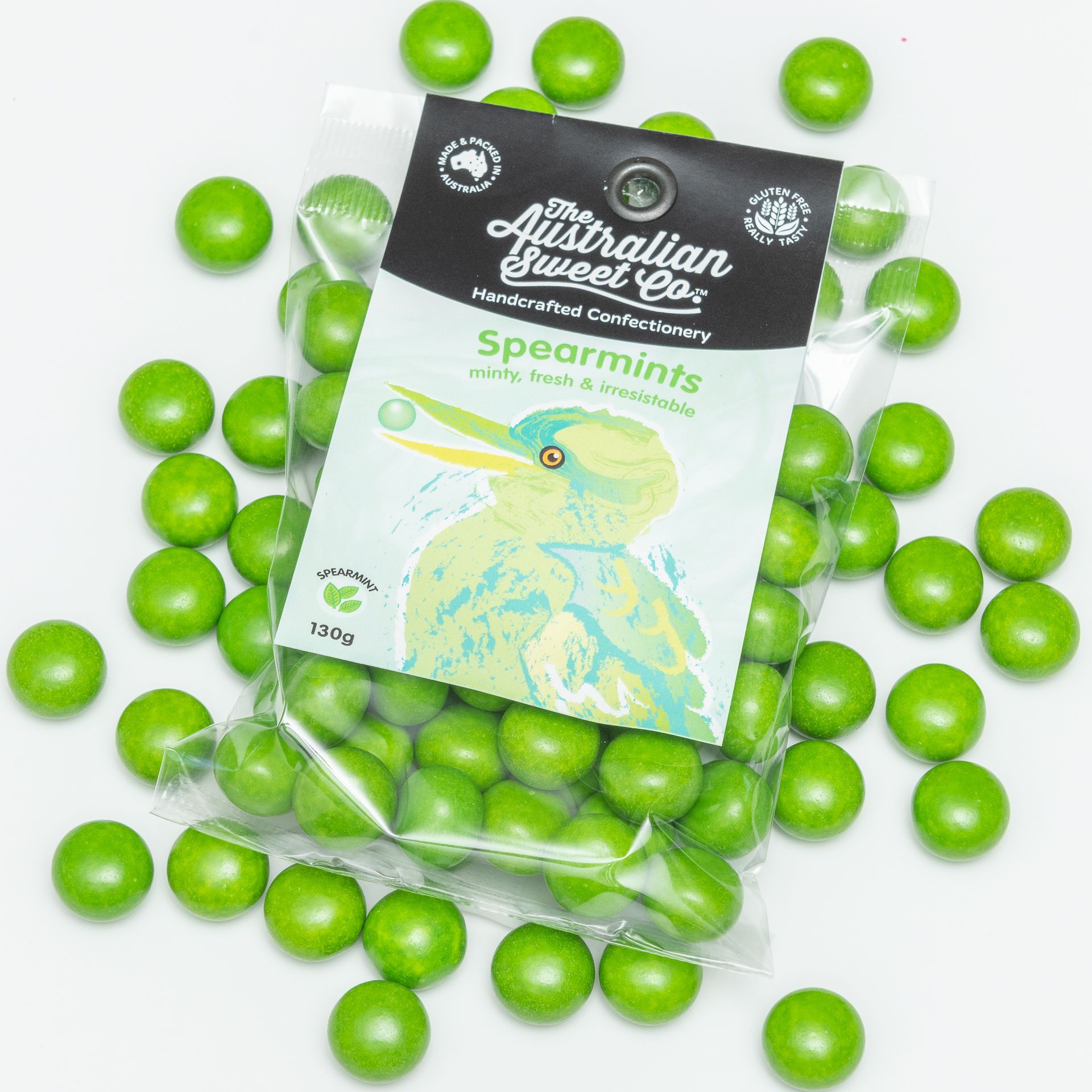 Green spearmint gum balls in a clear bag with Australian label, scattered on a white background