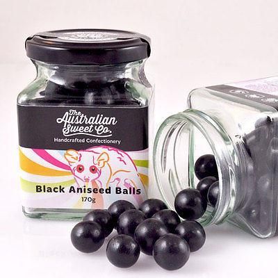 Jar and spilled black licorice balls with black and white label on a white background