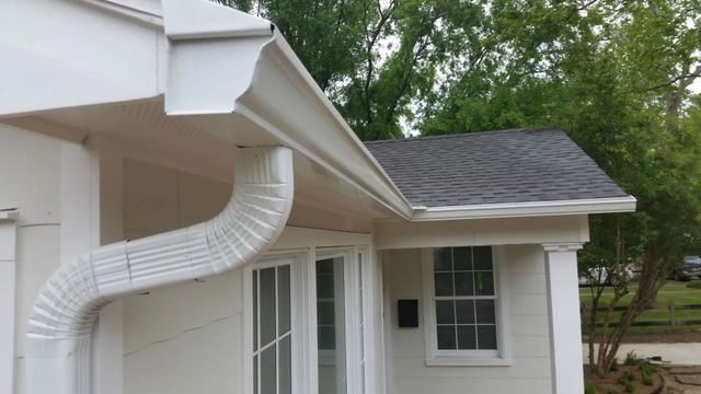 Beige house exterior with tan gutter system and windows.