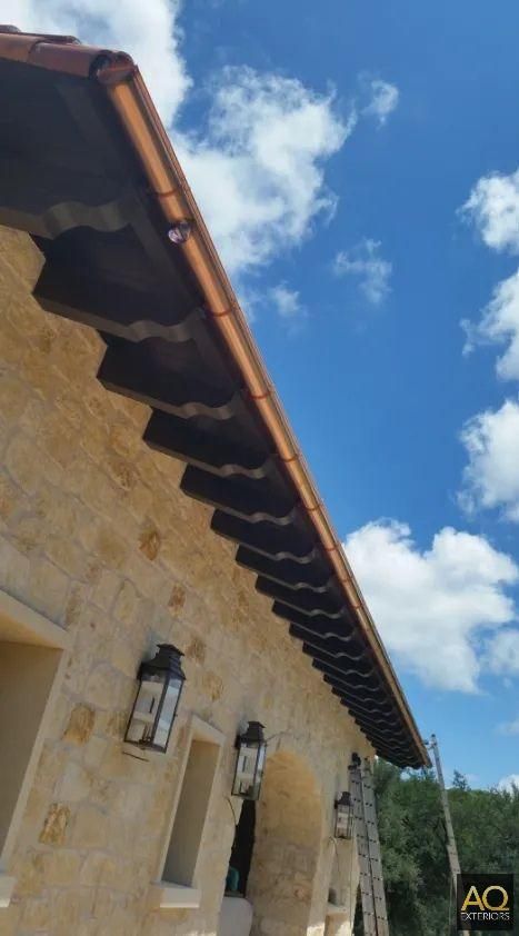 Stone building with brown roof, blue sky, and white clouds.